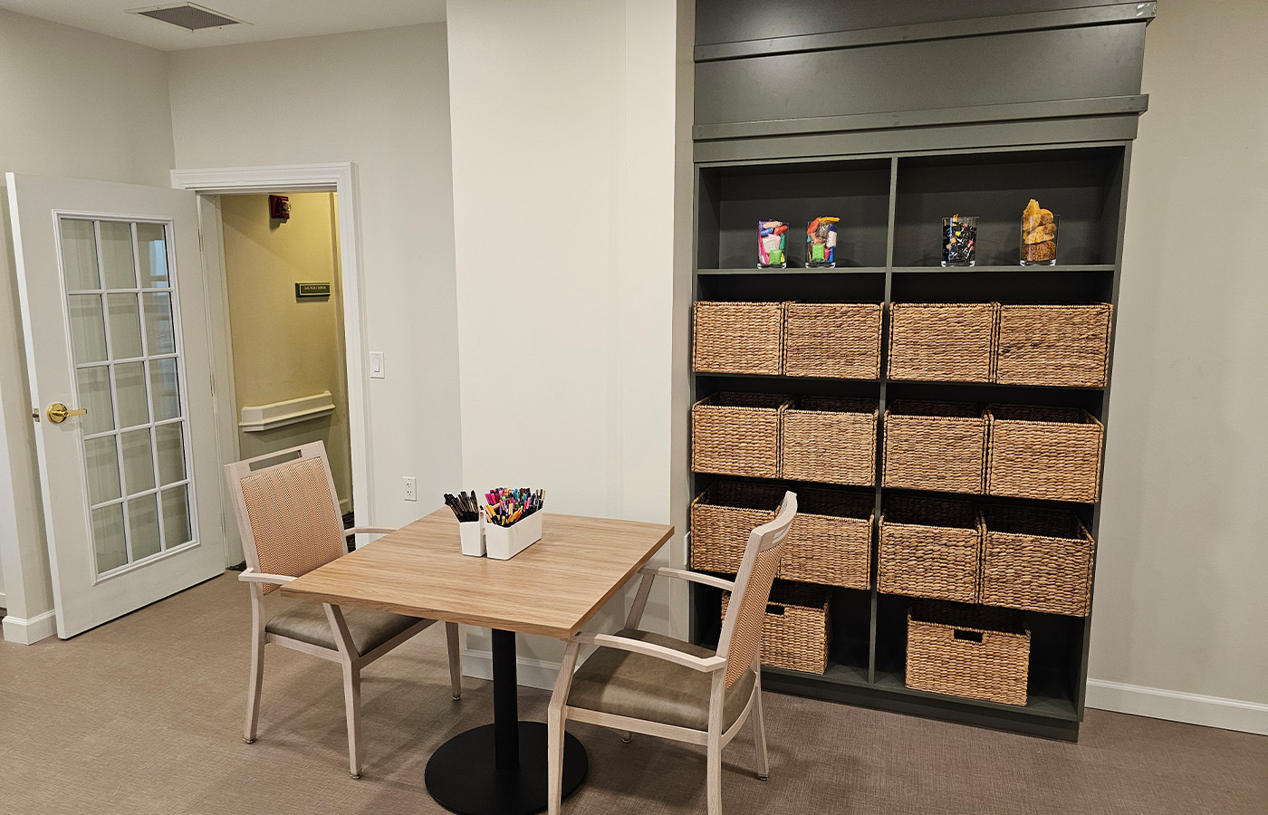 A table and chairs with baskets on the shelf.