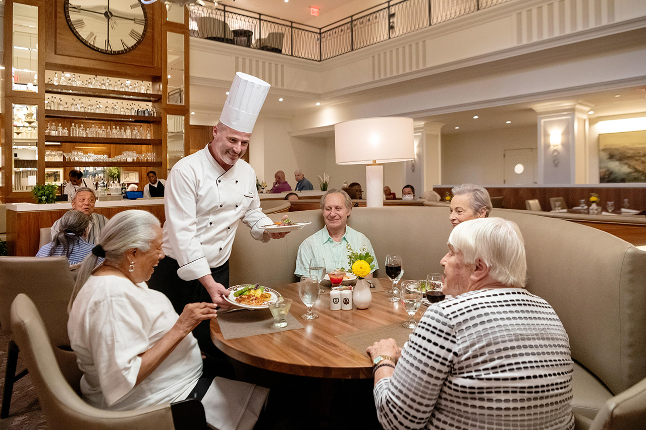 Chef greets table with a group of people.