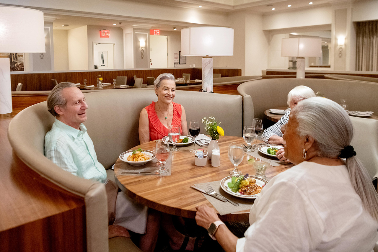 Group of people gather at table to eat.