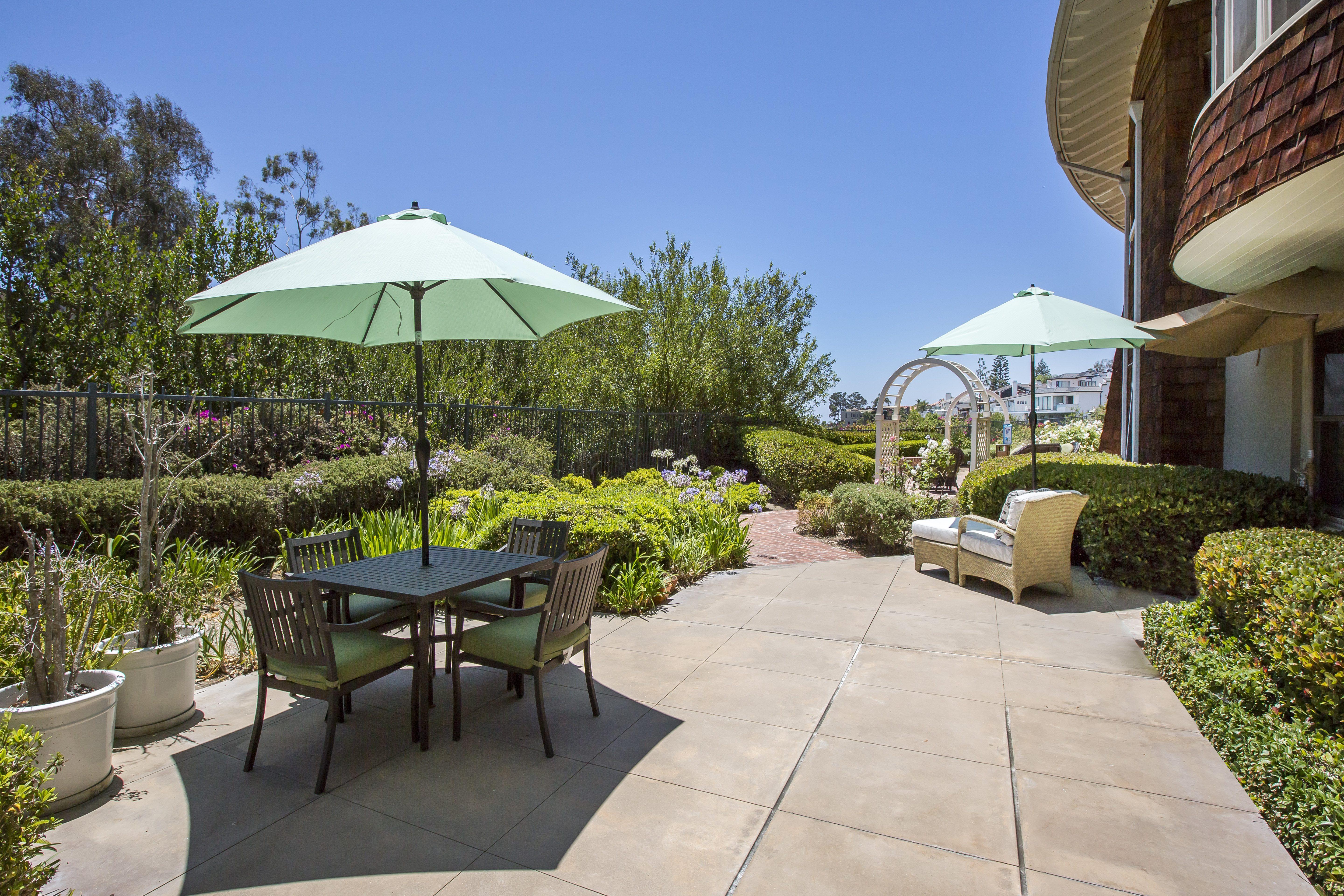 Patio and garden with tables, chairs and umbrellas.