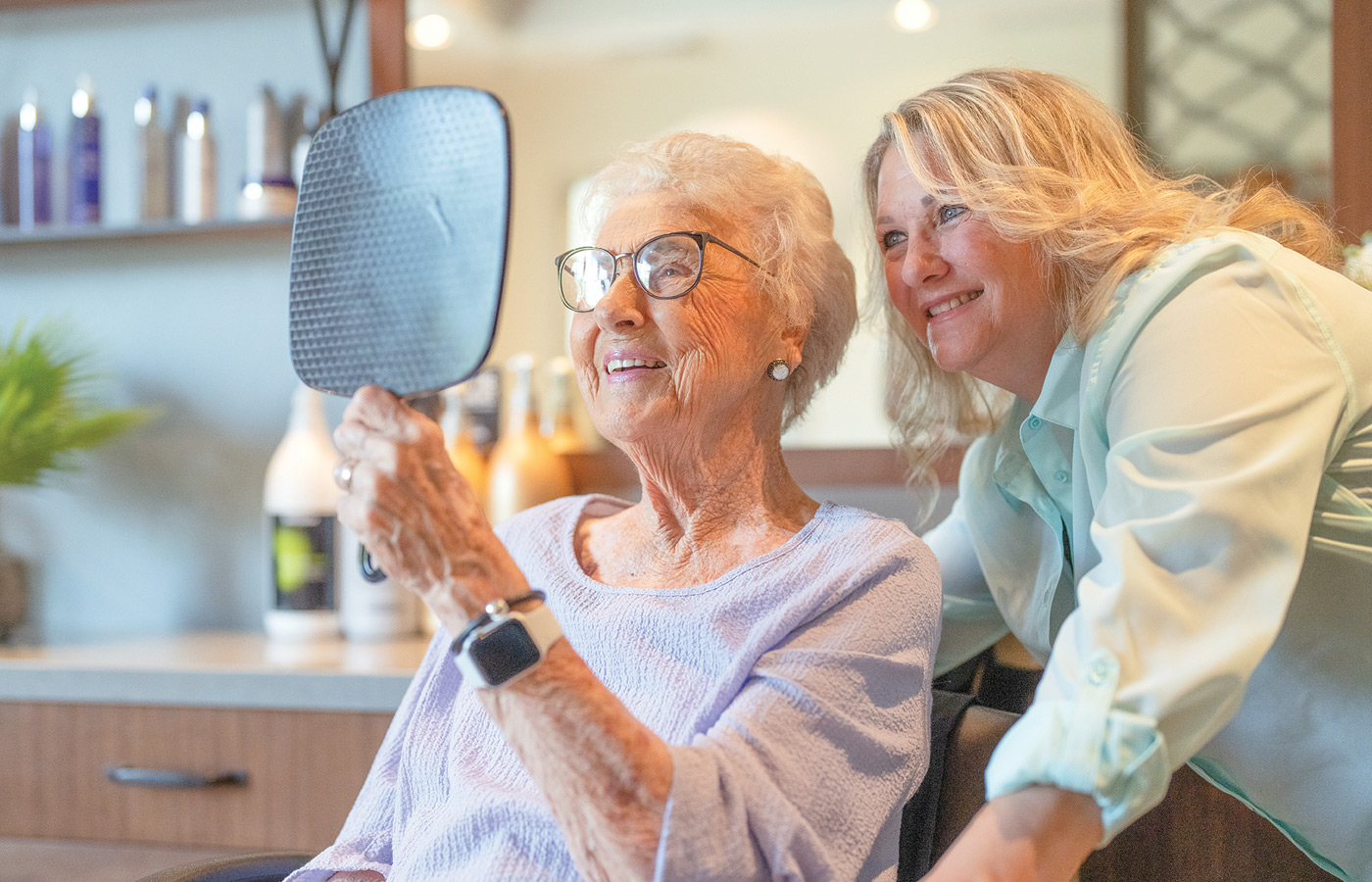 A resident is looking at their hair at the salon.