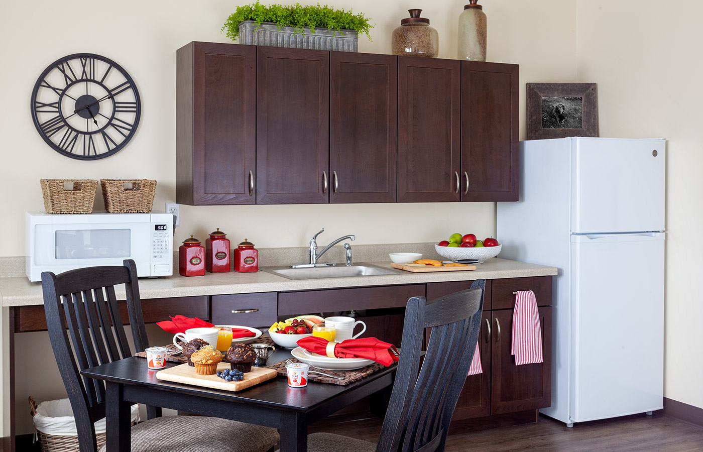 Dining table with chairs near kitchen with refrigerator.