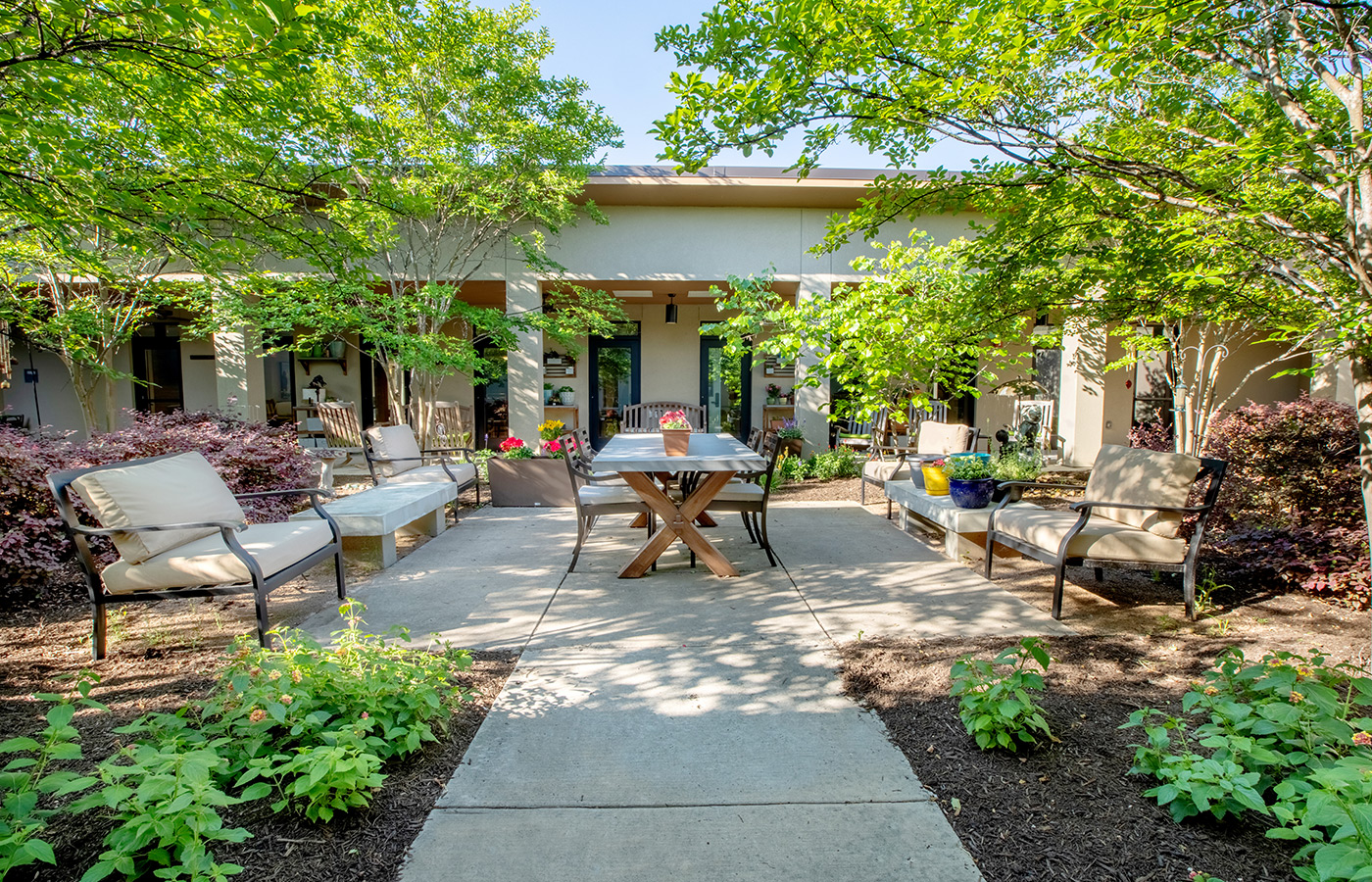 The memory care garden area with seating, a table and lots of plants.