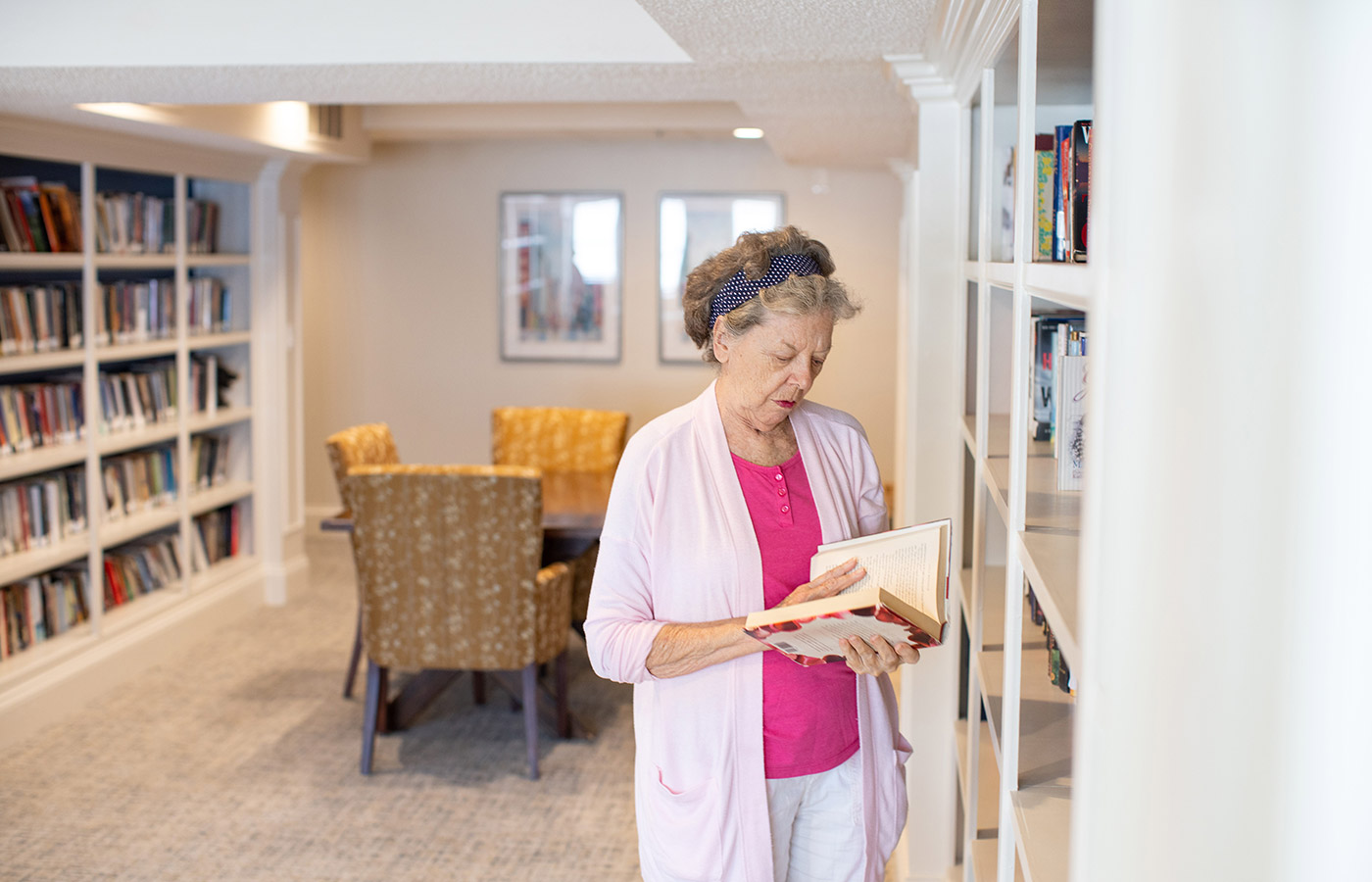 A resident is holding a book in the library at The Fountains at Crystal Lake.