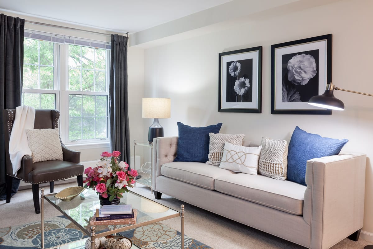 Furnished living room space with sofa, large window, coffee table, and arm chair.