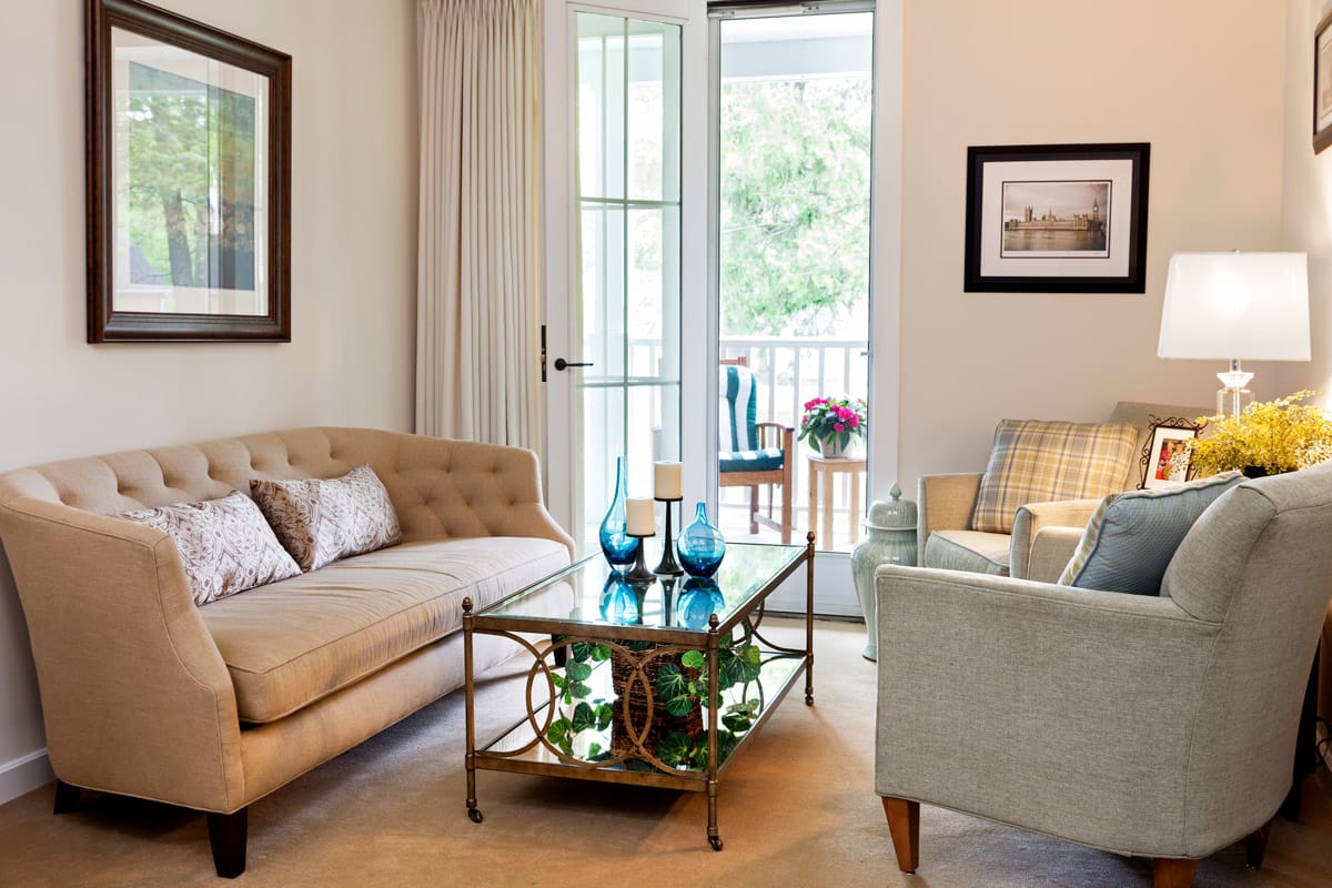 Furnished living room space with sofa, large window, coffee table, and arm chair.