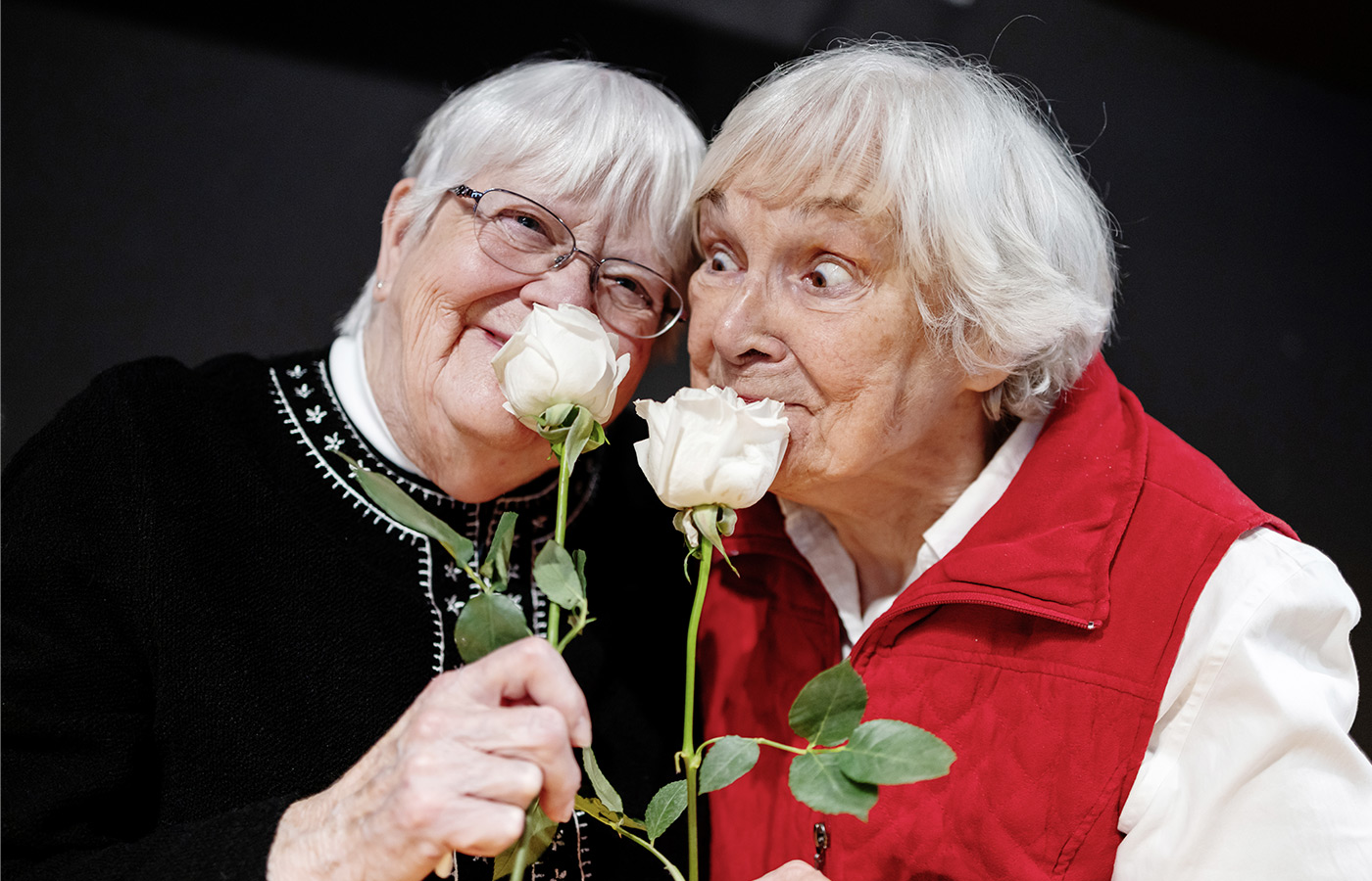 Two people smelling roses.