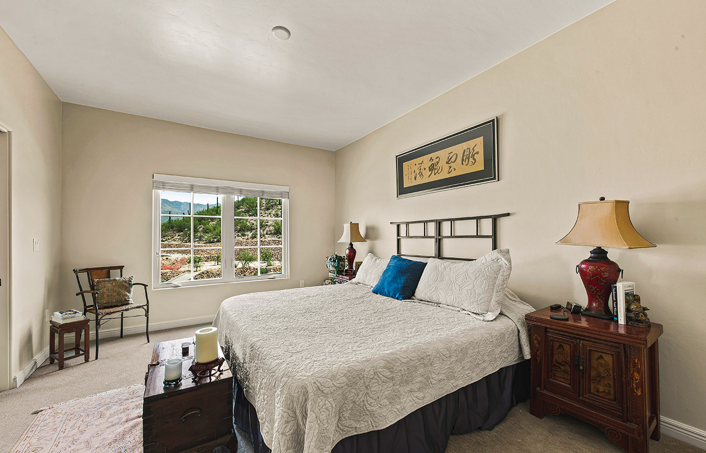 Furnished bedroom with bed, drawers, and soft lighting.