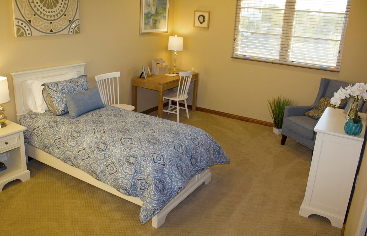 Furnished bedroom with bed, drawers, and soft lighting.