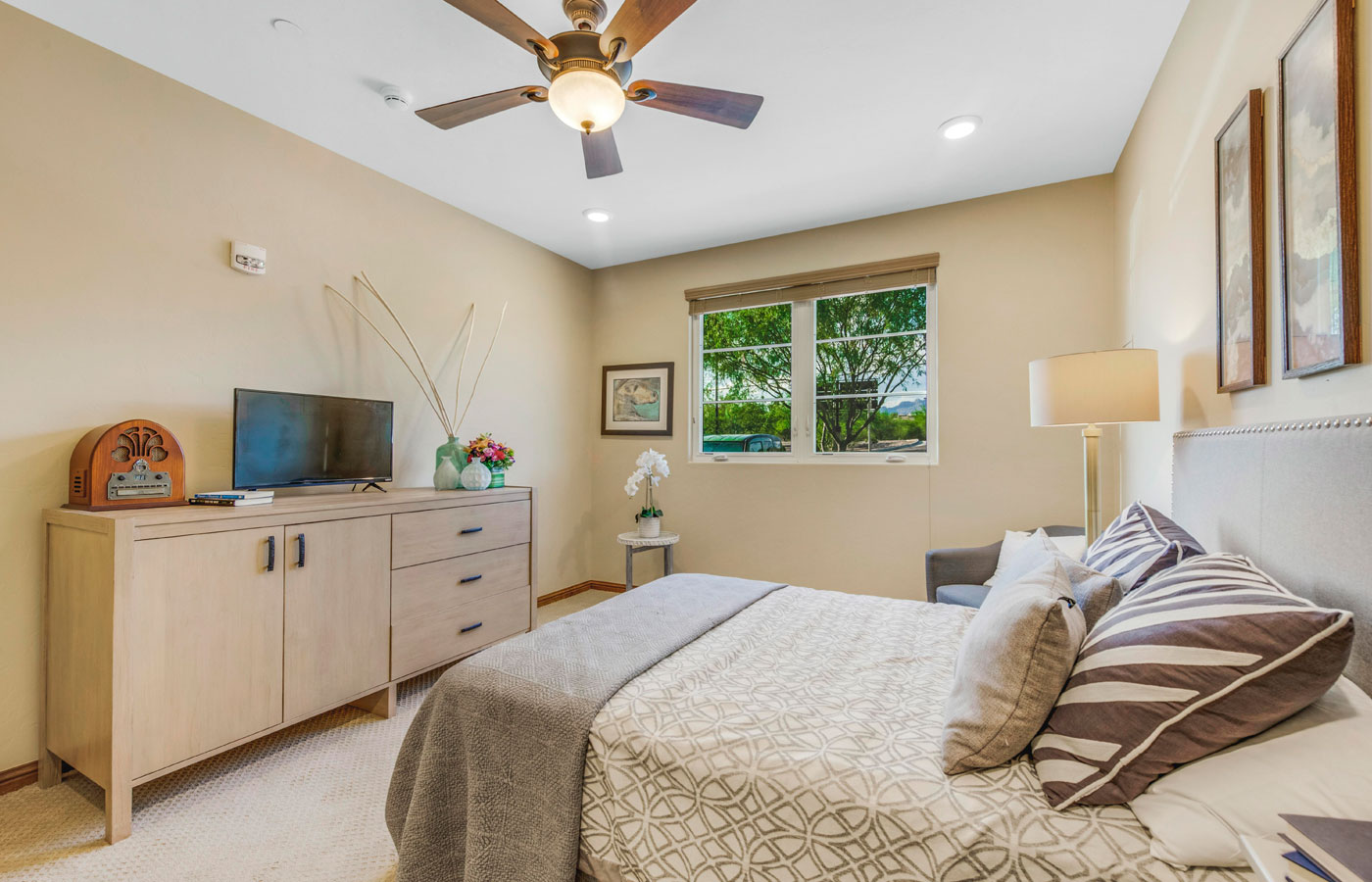 Furnished bedroom with bed, drawers, and soft lighting.