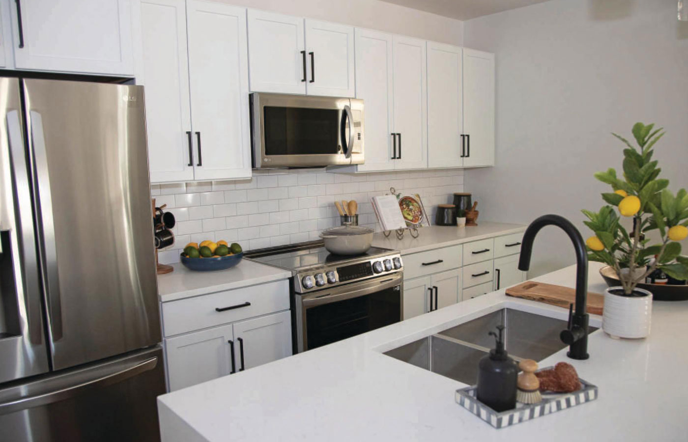 A modern kitchen featuring white cabinetry and stainless steel appliances in a residence.