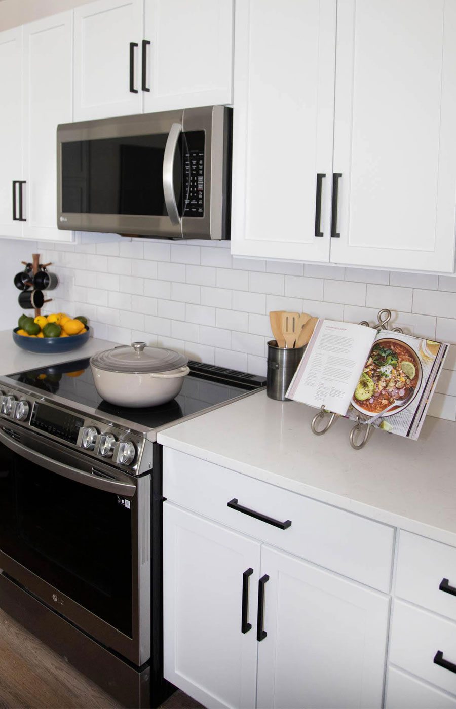 A modern kitchen showcasing a stainless steel electric stove and white cabinetry in a model residence.