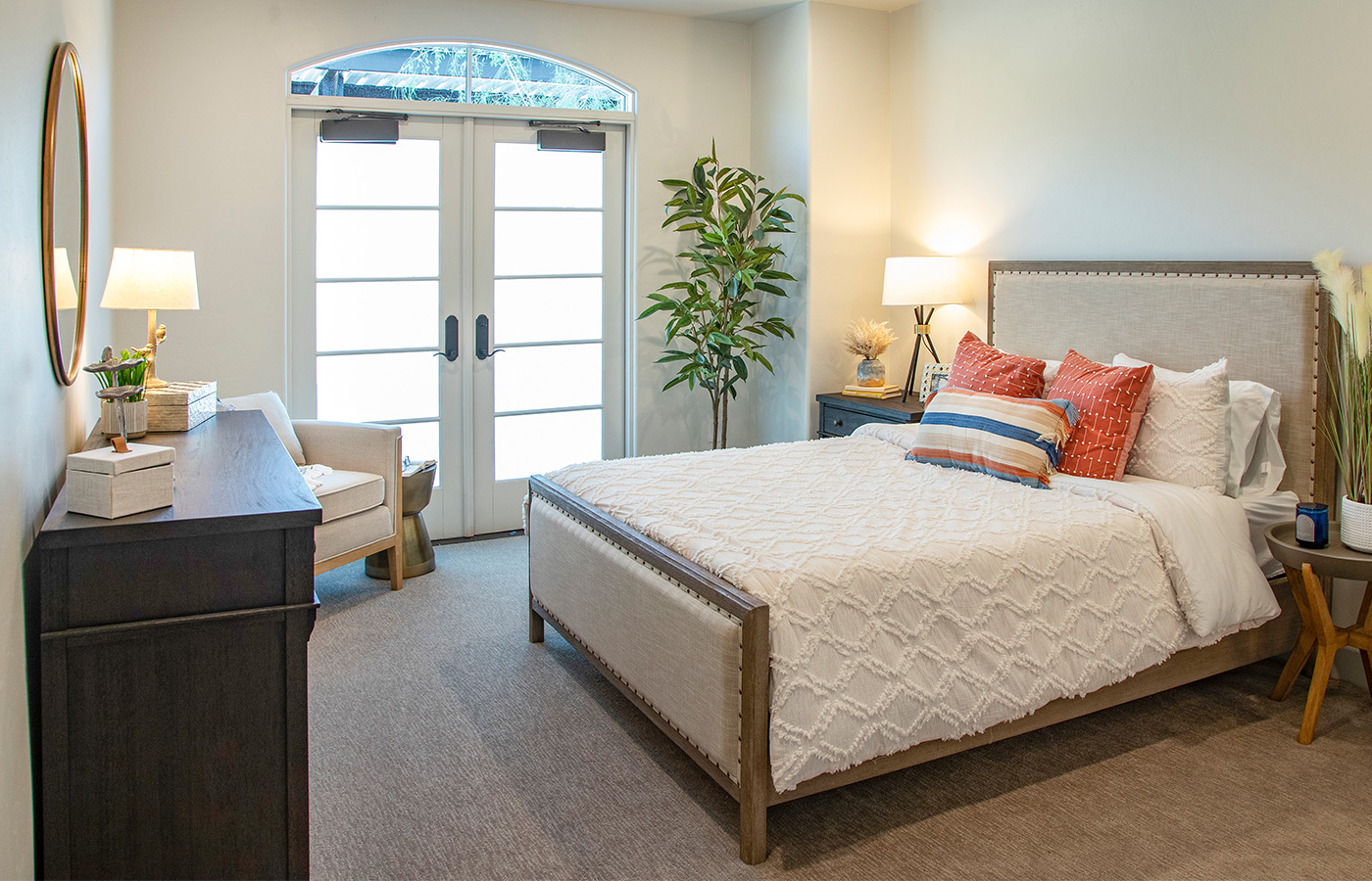 Furnished bedroom with bed, drawers, and soft lighting.