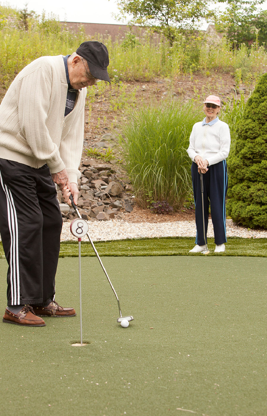 Two residents are putting on a putting green.