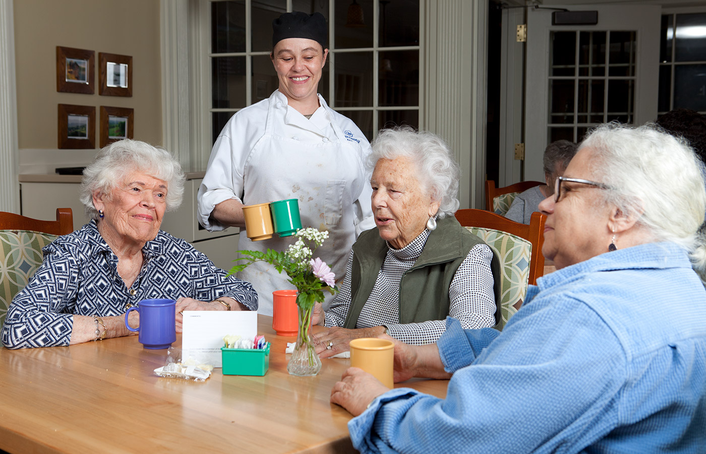 Three residents are in a dining area at The Watermark at East Hill.