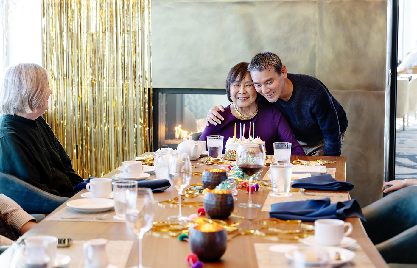 A person hugging another at a birthday celebration.