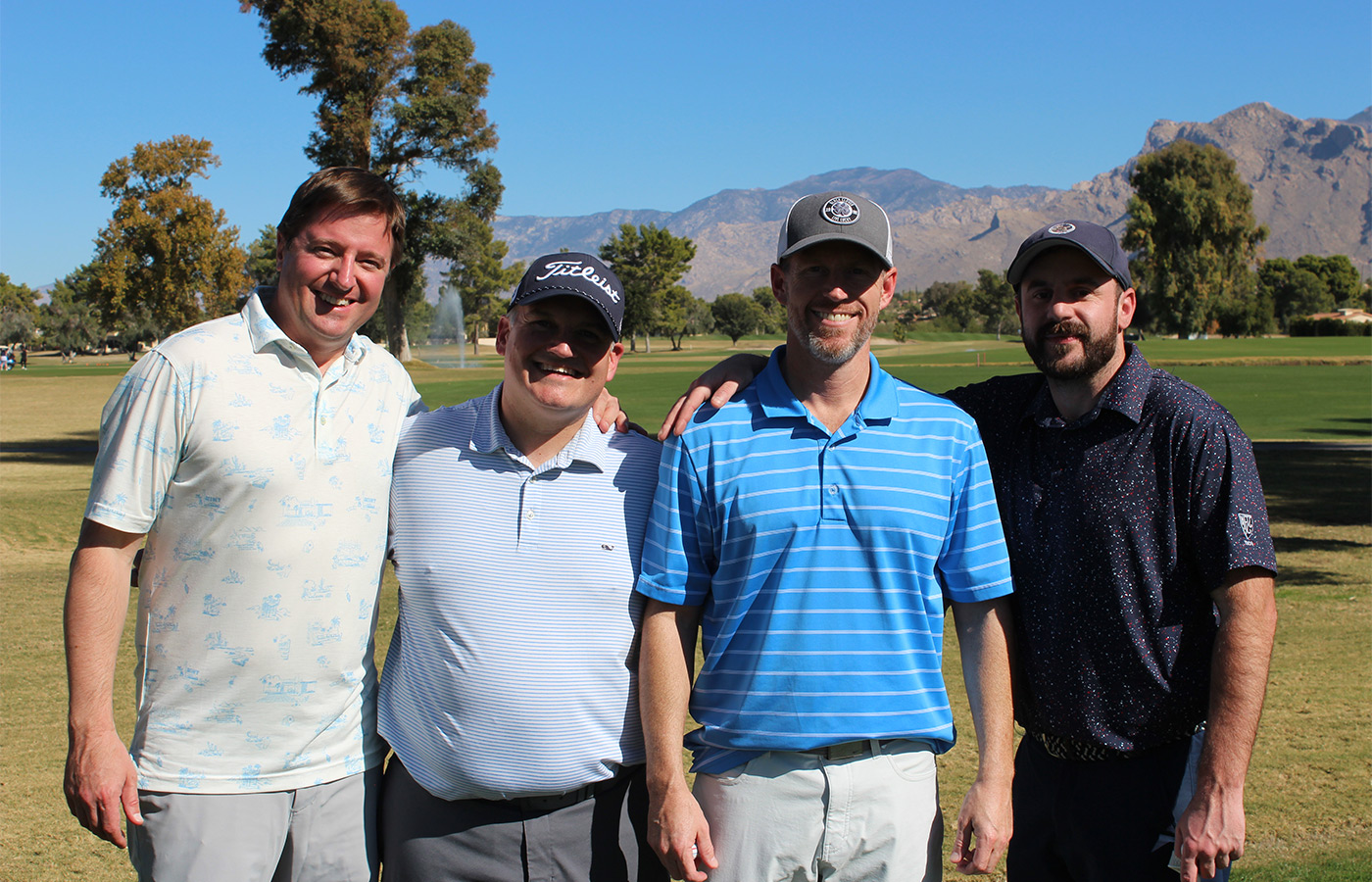 People standing on a golf course smiling.