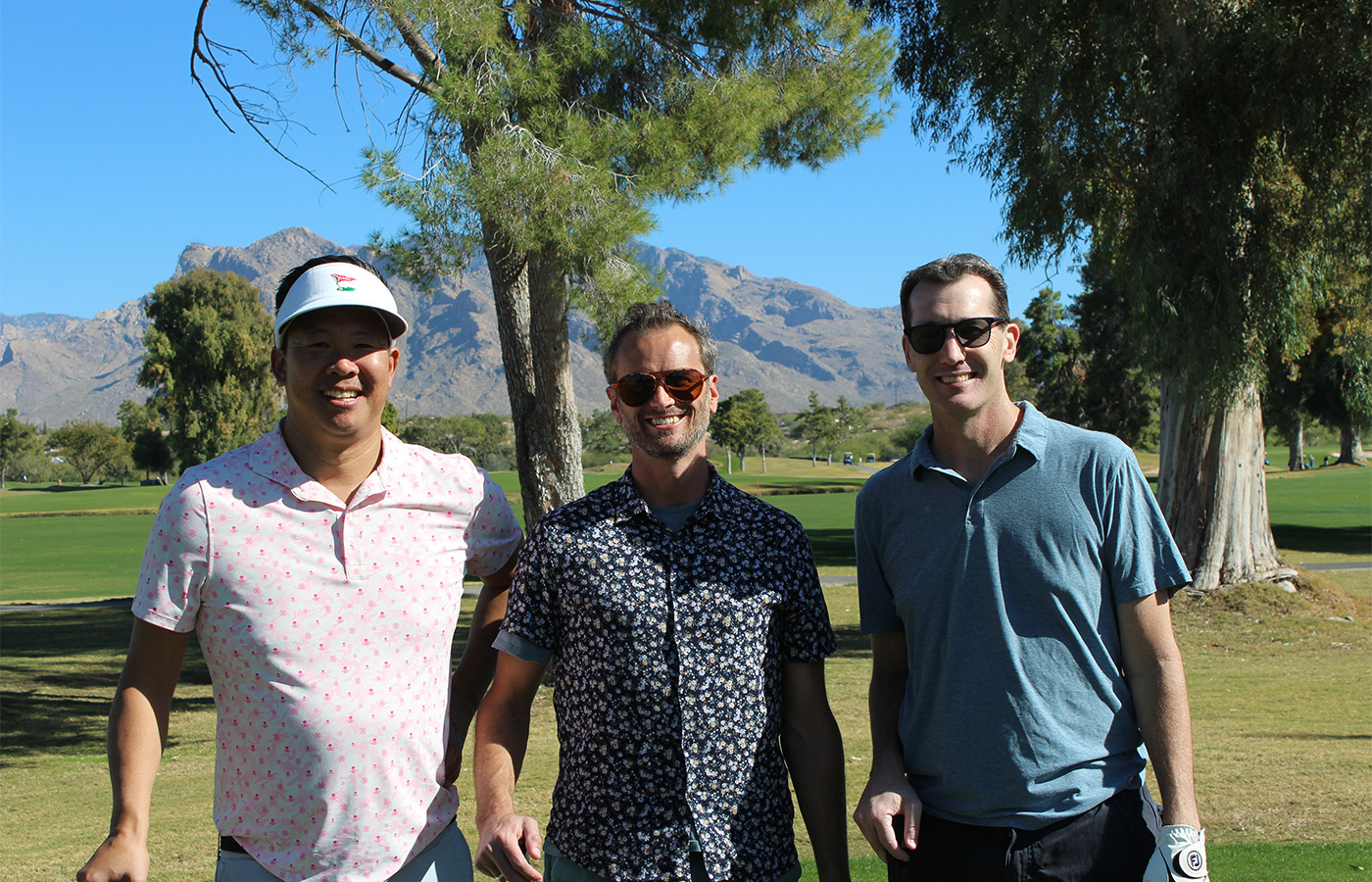 People standing on a golf course smiling.