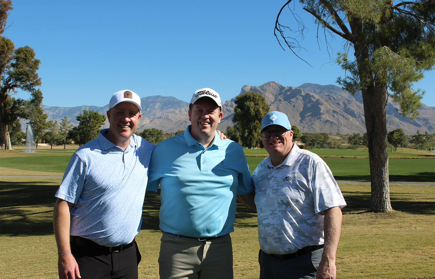 People standing on a golf course smiling.