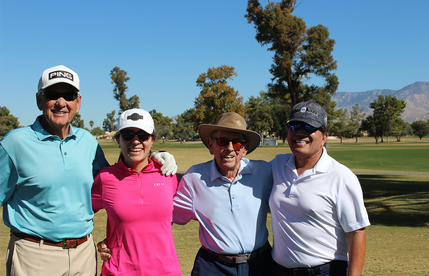 People standing on a golf course smiling.