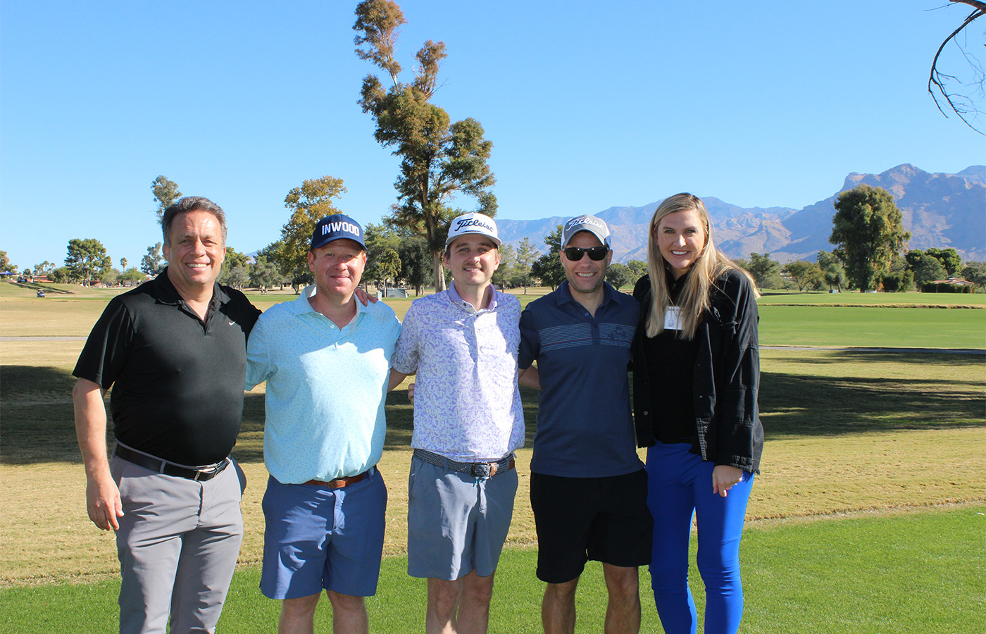 People standing on a golf course smiling.