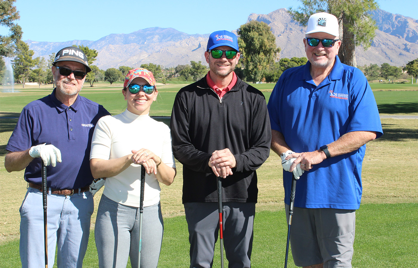 People standing on a golf course smiling.