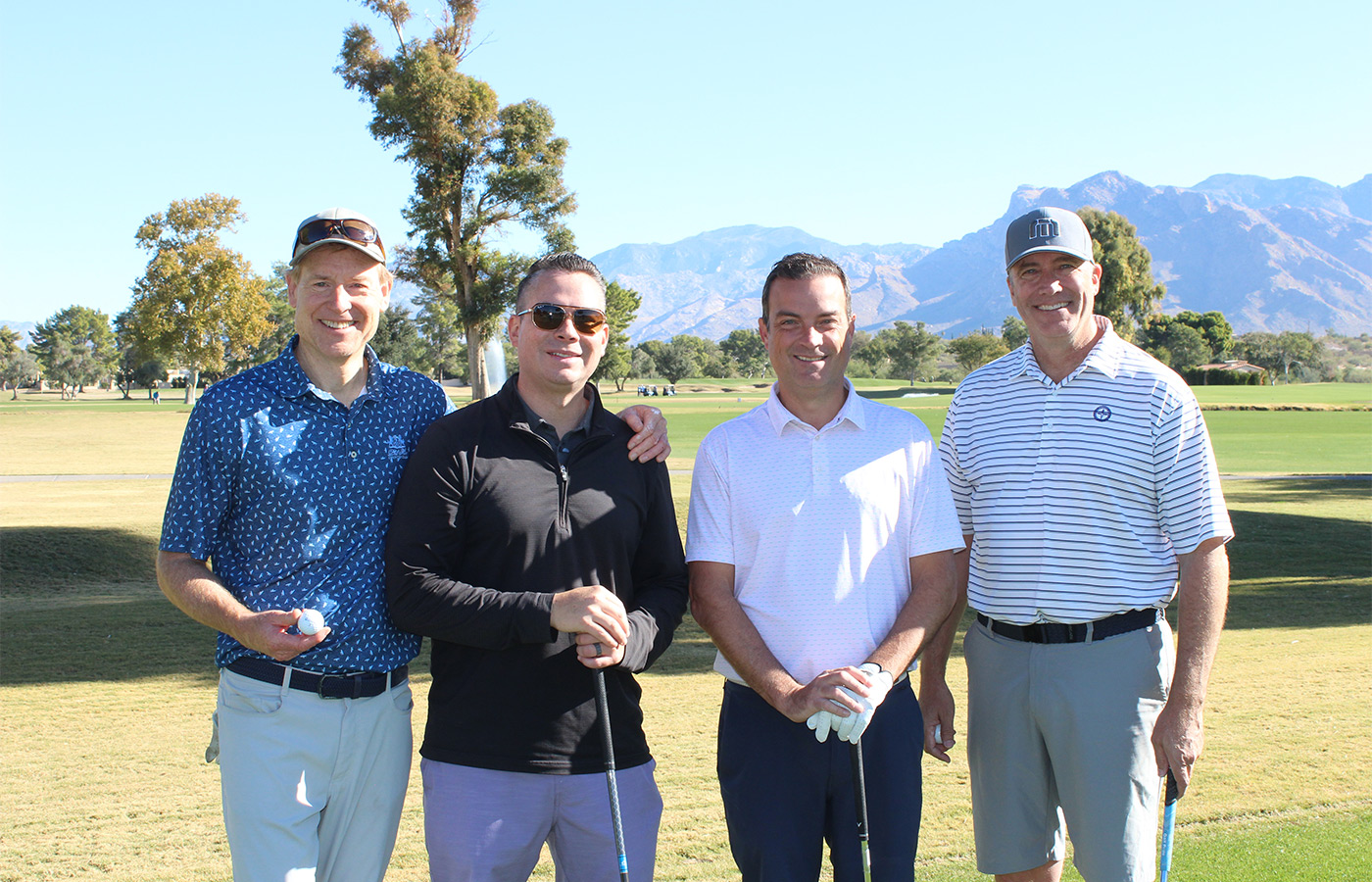 People standing on a golf course smiling.