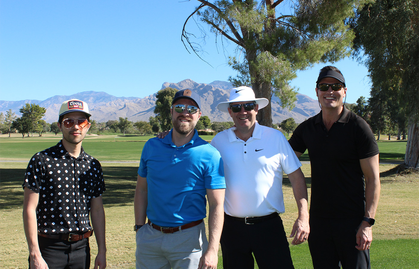 People standing on a golf course smiling.