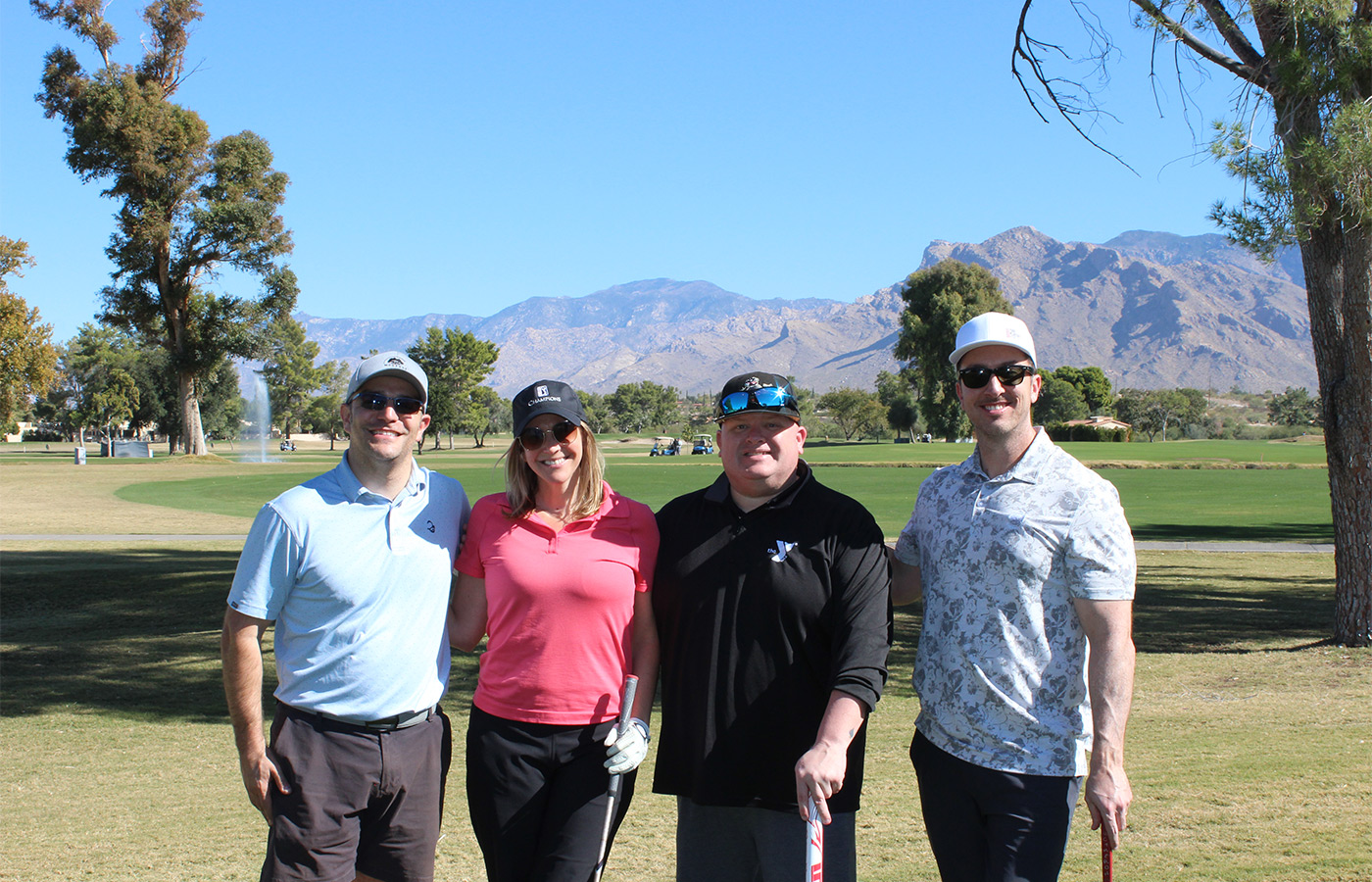 People standing on a golf course smiling.