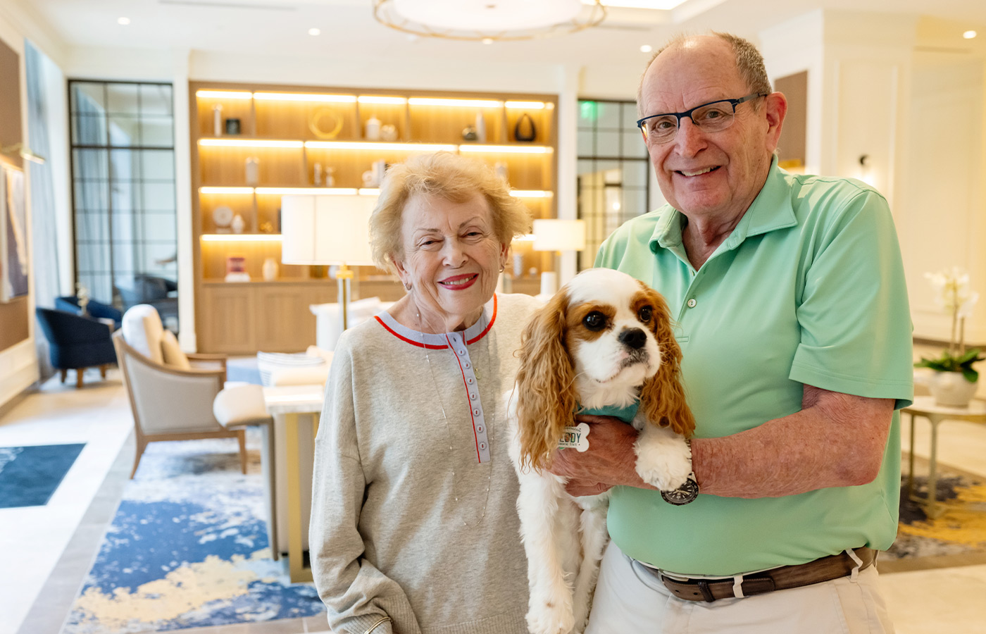 Two people holding their dog in the lobby.