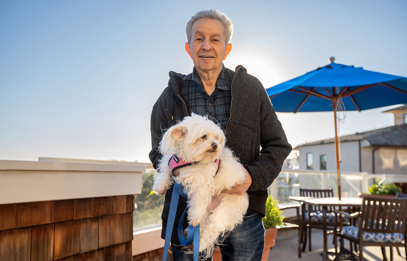 A resident is on the patio outside holding a fluffy white dog.