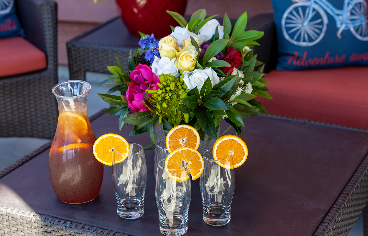 Pitcher of tea with glasses and flowers.