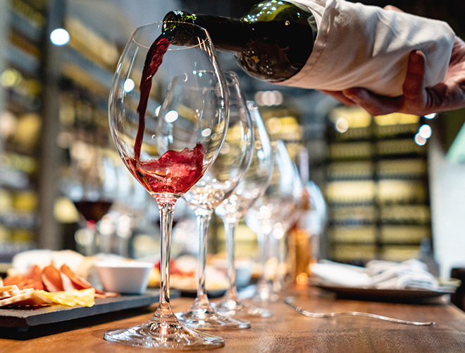 Someone pouring wine into a glass.