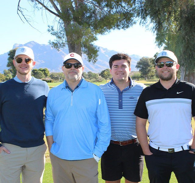 Four golfers standing outside.