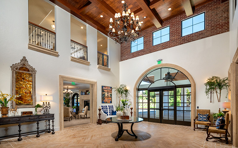 A lobby area with a tall ceiling and chandelier. 