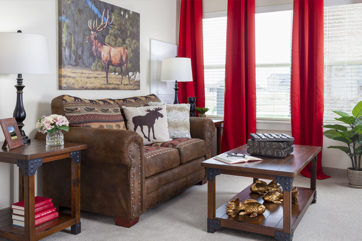 Furnished living room space with sofa, window, drapes, and coffee table.