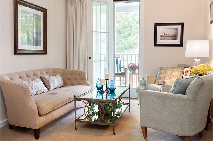 Furnished living room space with sofas and coffee table and balcony.