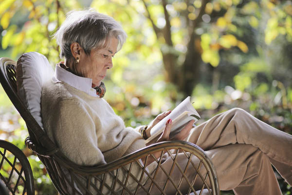 Pensive resident reads book while sitting on a cozy chair.