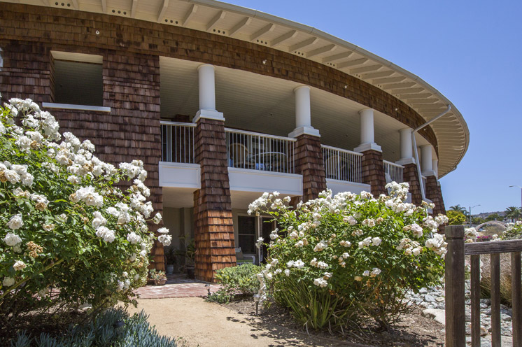 Exterior of Crown Cove building with white flowers along the front.