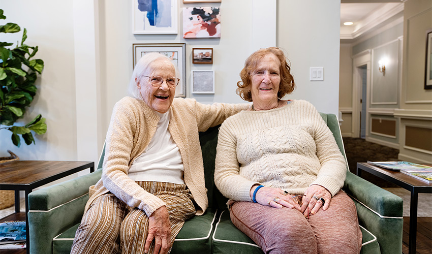 Two people sitting on a couch laughing.