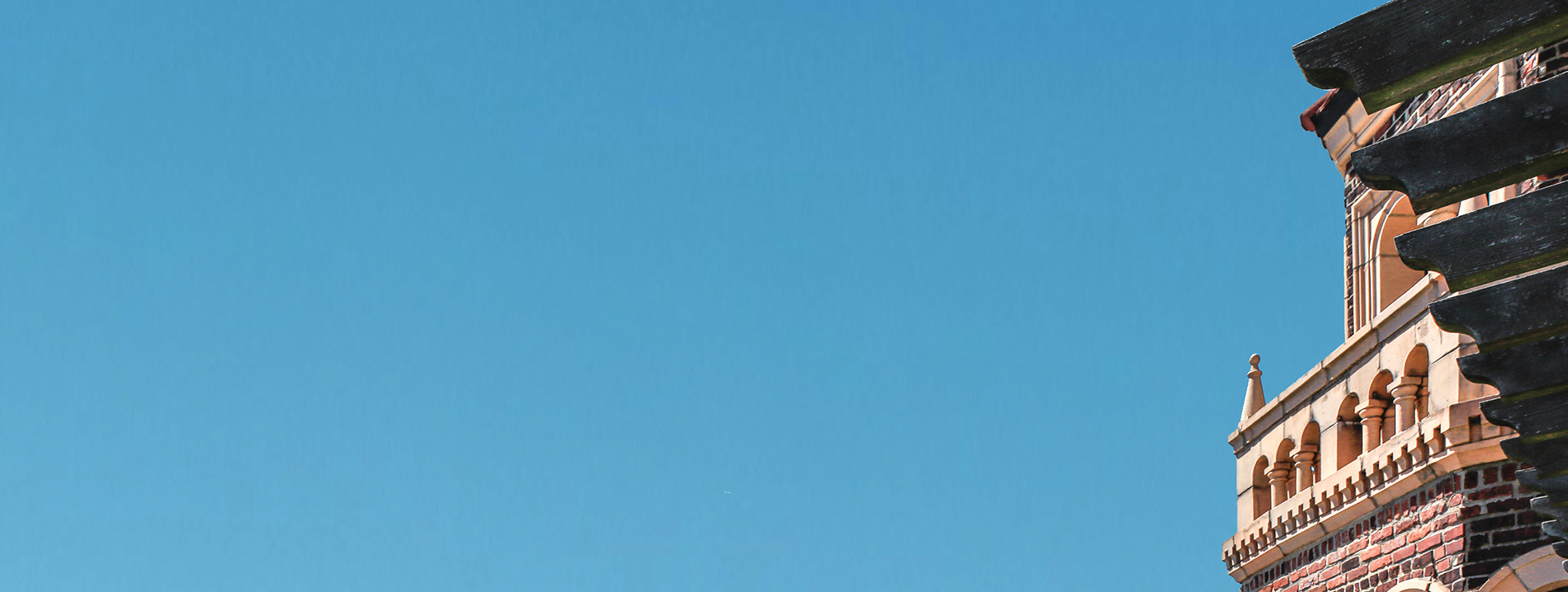 Blue sky and portion of a brick tower.