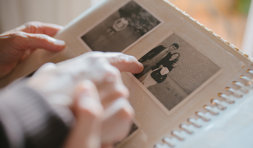 Close up of hands pointing at family photos in an album.