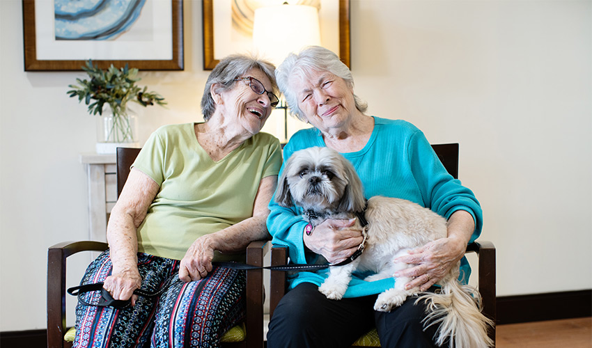 Two people sitting with a dog.