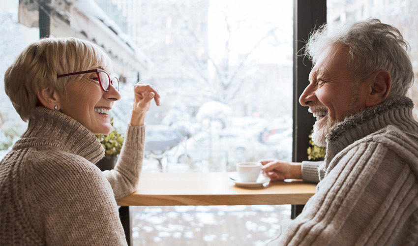 two friends drinking a cup of coffee in front of a snowy window