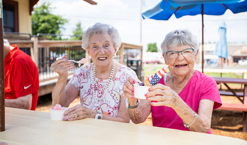 Two people outside eating ice cream.