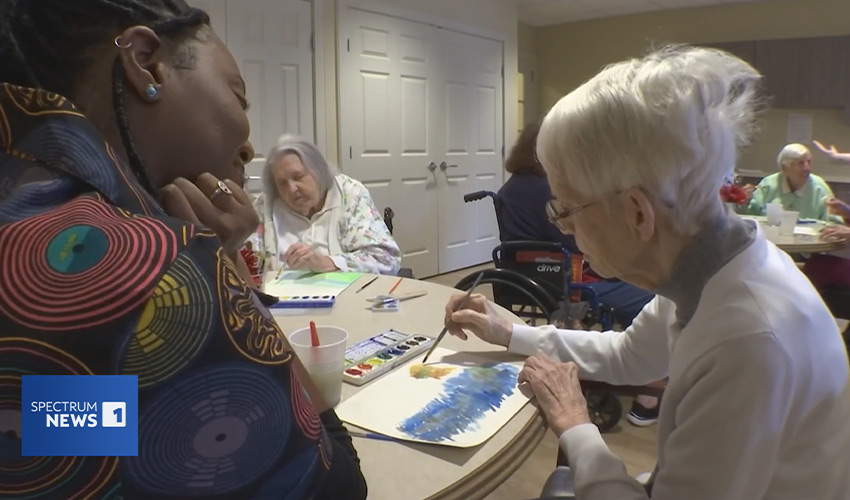 A group of people at a table painting.