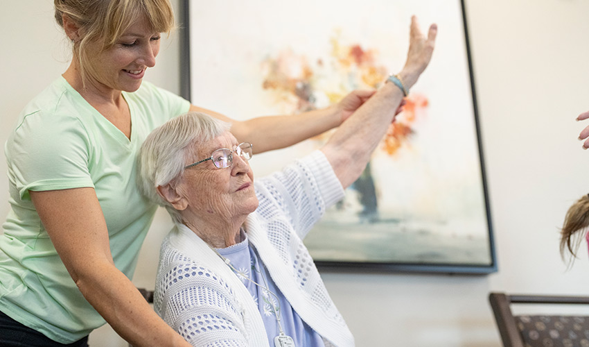 A trainer helping a senior woman stretch.