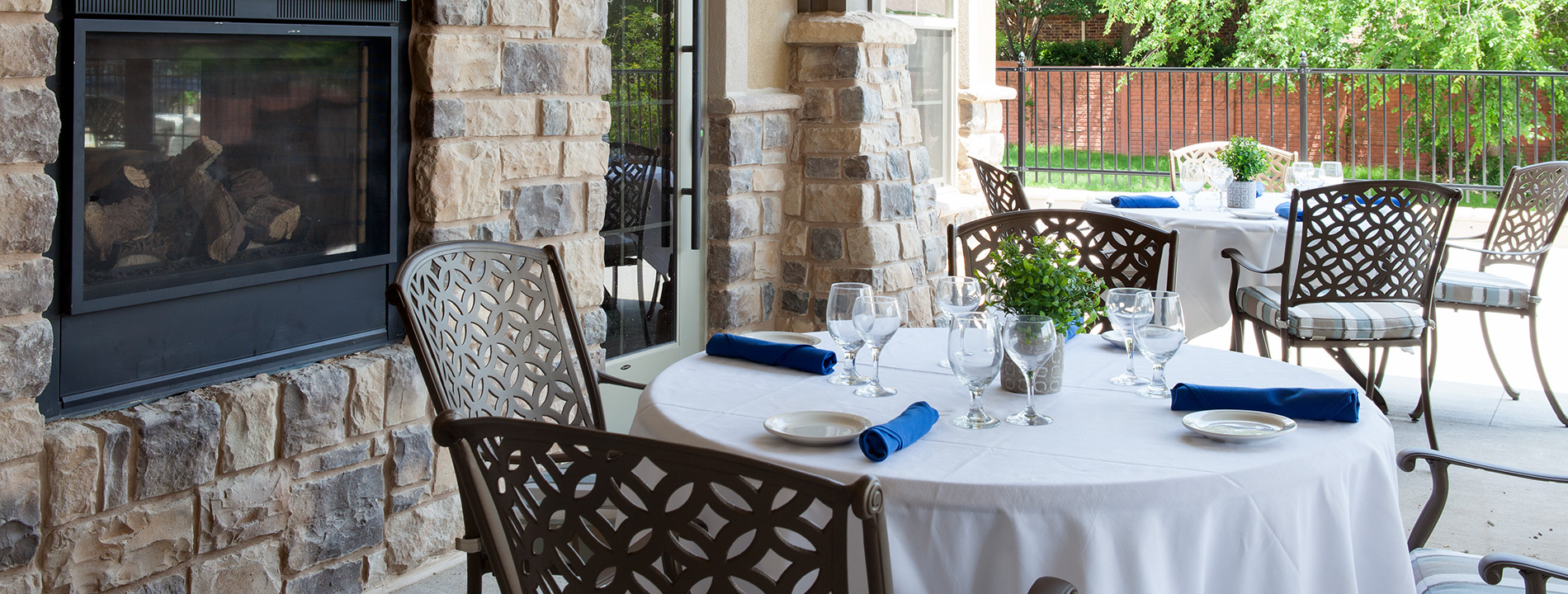 White table clothed tables with chairs and blue napkins.