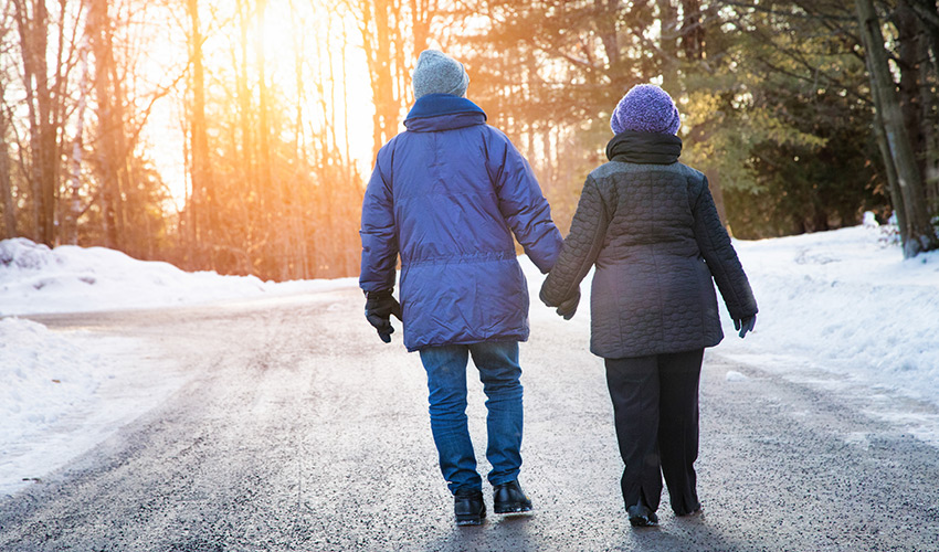 A couple walking down a snowy road.