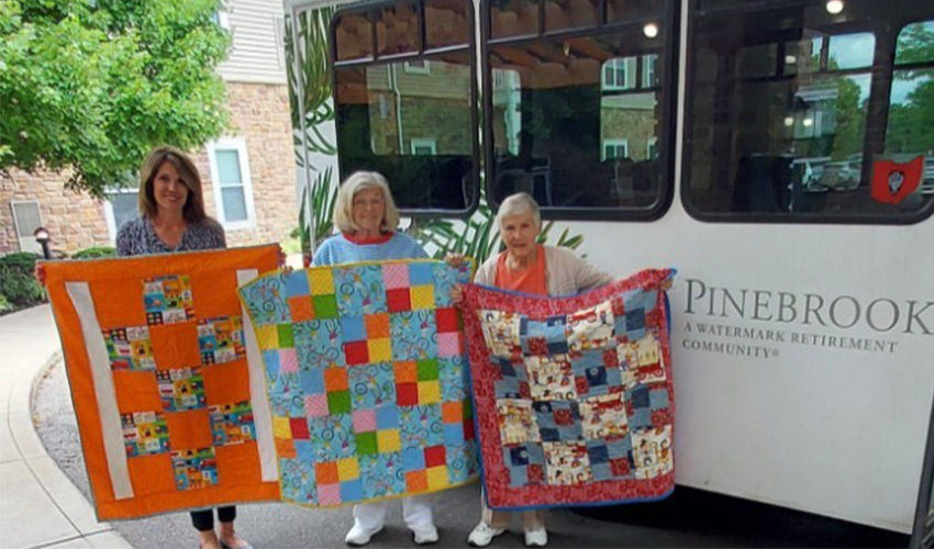 People holding up quilts.